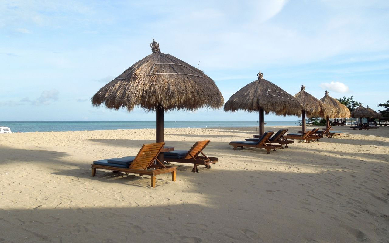 beach chairs under tiki hut umbrella